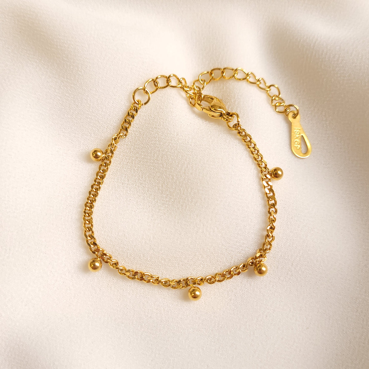 Children's Dangling Dots Bracelet arranged in a circle, featuring a gold-tone curb chain with small dangling ball charms.