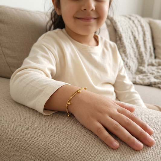 Children's Dangling Dots Bracelet worn on a child's wrist, showing the gold-tone chain and dangling ball charms.