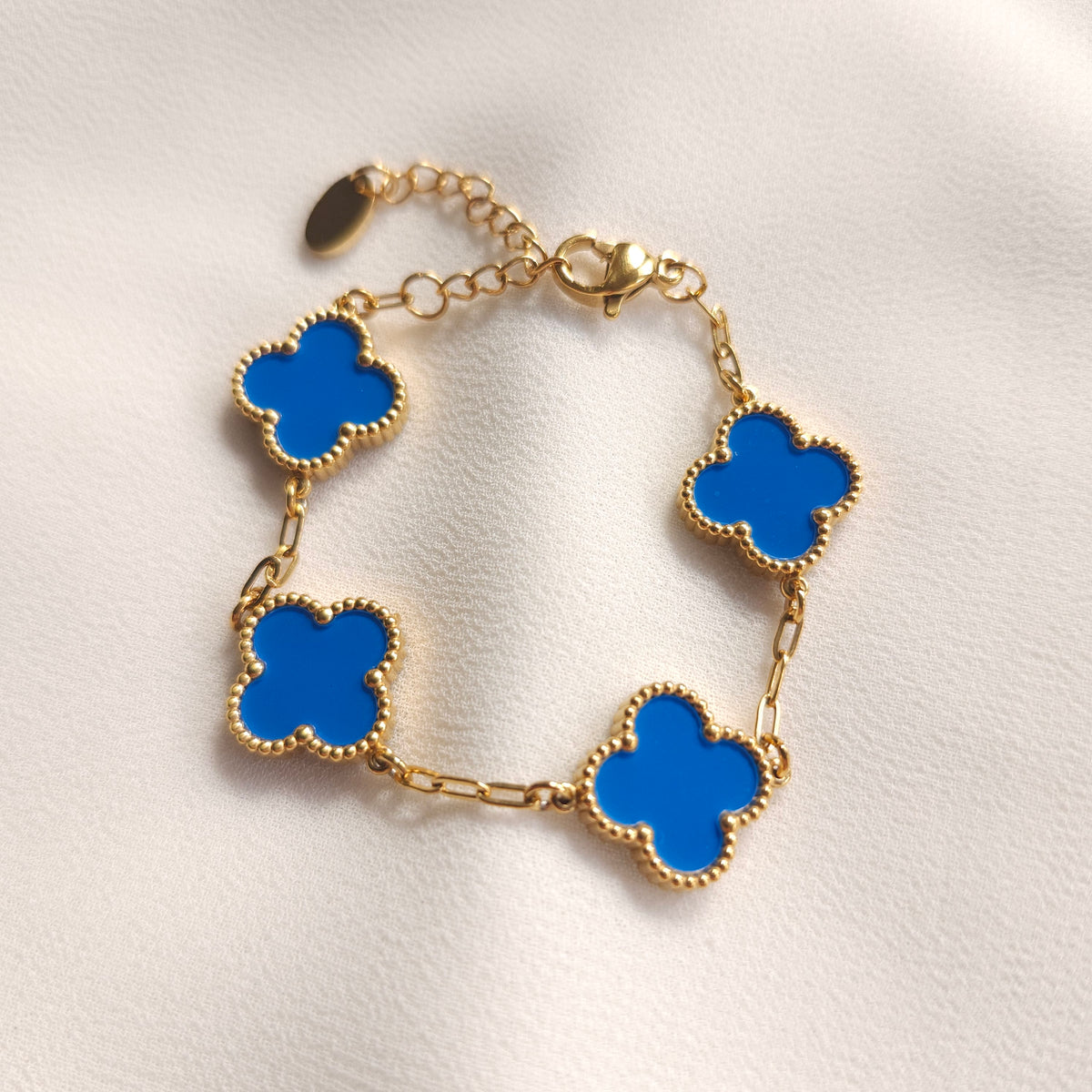 Children’s gold-tone bracelet with four bright blue clovers and beaded borders.