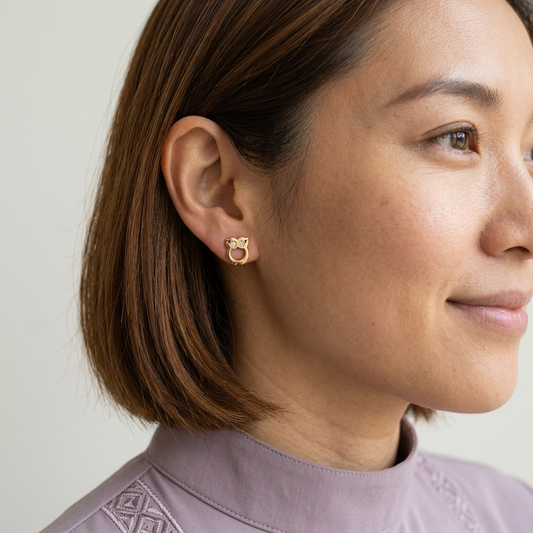 Close-up of a model wearing a gold Owl Earring with clear stone eyes and an open centre.