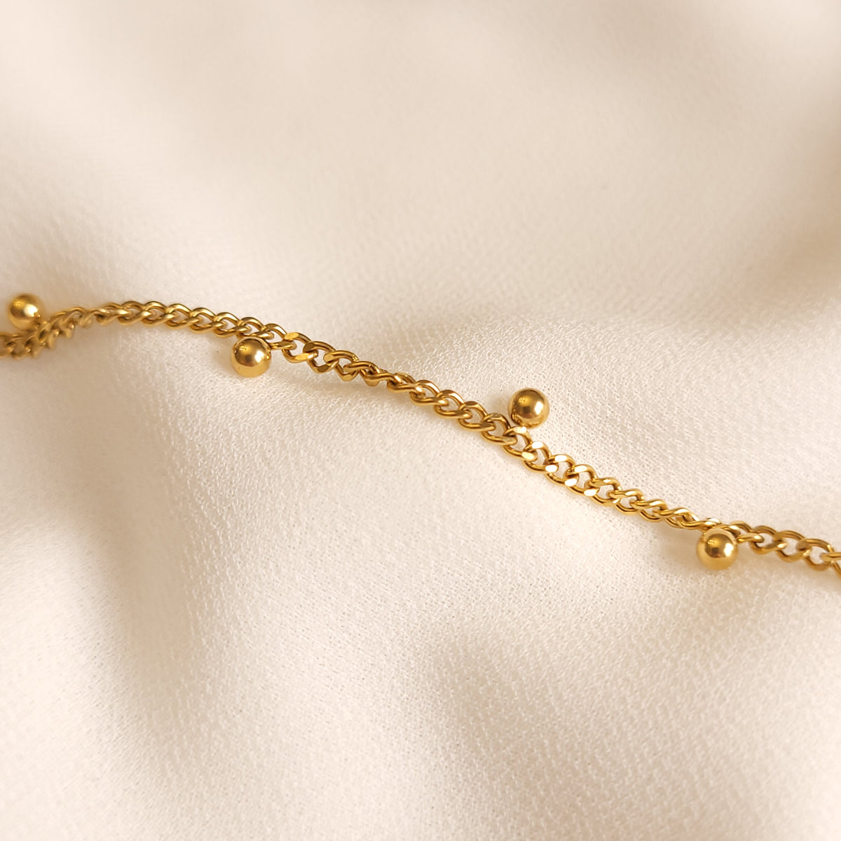 Close-up of the Dangling Dots Bracelet showing its curb-chain links and polished round charms.