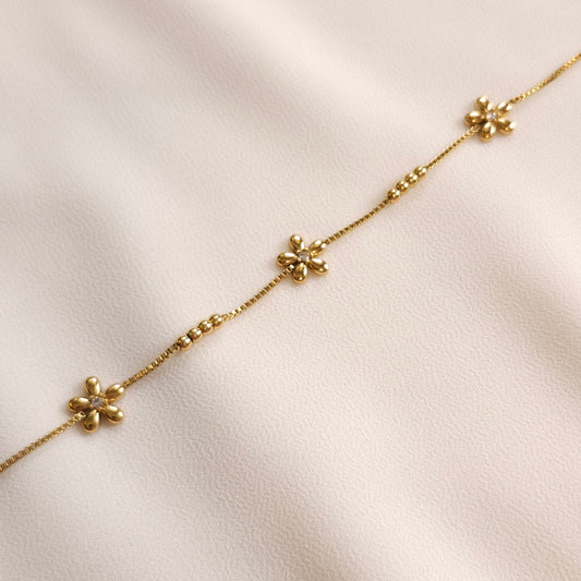 Close-up of the gold Daisy Chain Anklet showing five-petal flowers and four-bead groups spaced along the chain