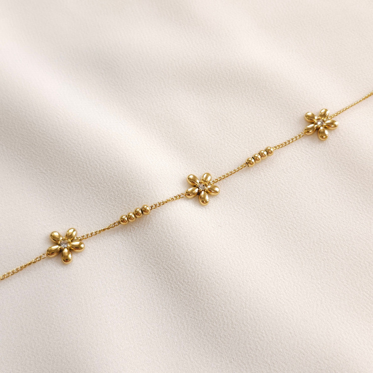 Close-up of the gold Daisy Chain Bracelet showing five-petal flowers and spaced groups of four beads.