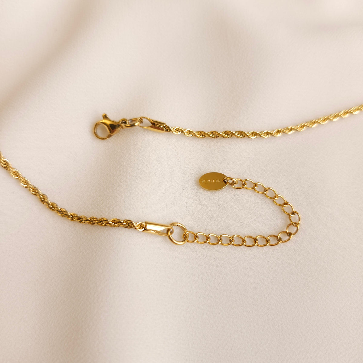 Close-up of the gold Lebanon Cedar Necklace showing its lobster clasp, extension chain and engraved tag.