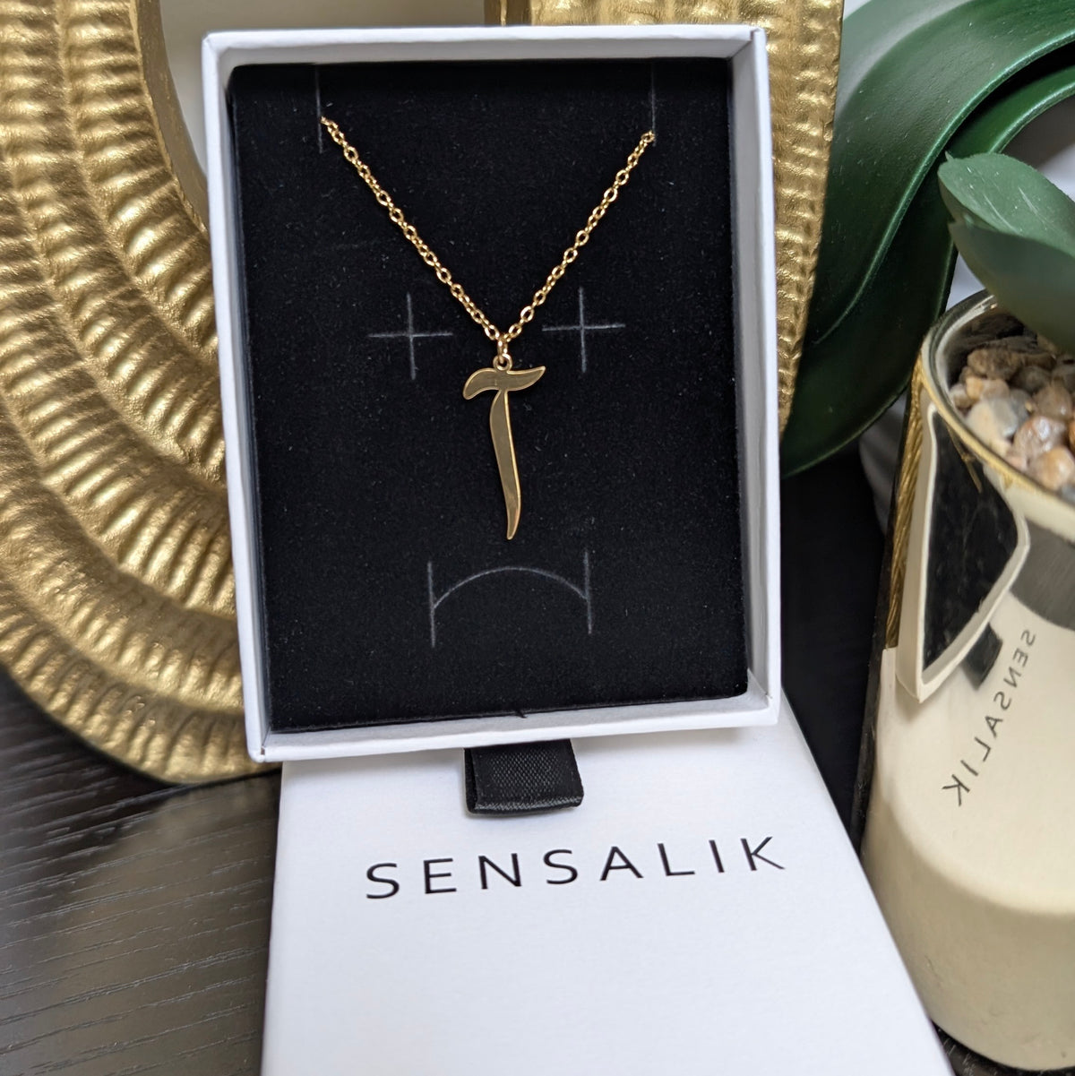 Gold-tone Arabic Initial Necklace with the letter Alif with Maddah (آ) displayed in a white Sensalik gift box.