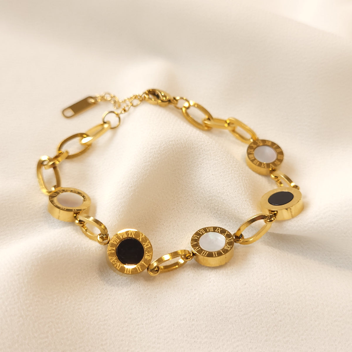 Gold-tone Roman Numeral Link Bracelet with alternating black and white round centres, engraved borders and oval connecting links.