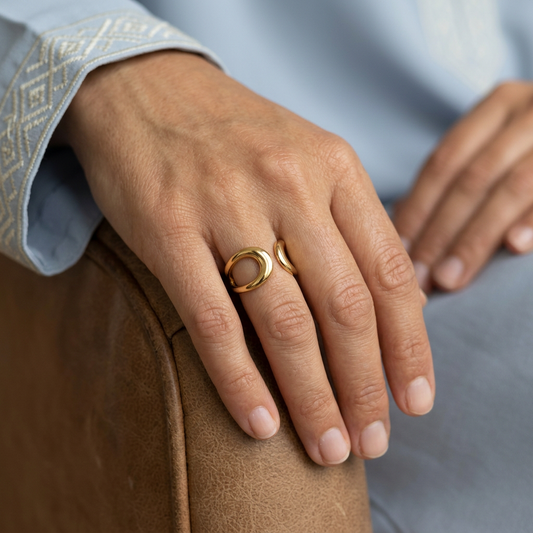 Gold Eclipse Ring worn on a model’s finger, showing its open curved design.