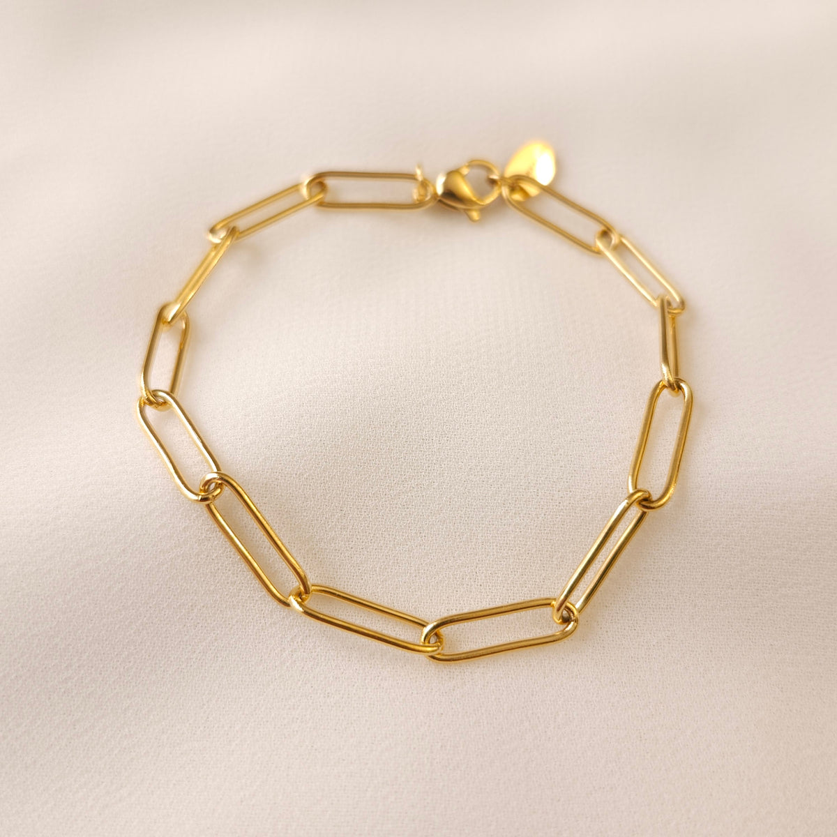 Gold Paperclip Bracelet with elongated rectangular links, a lobster clasp and an oval end tag.