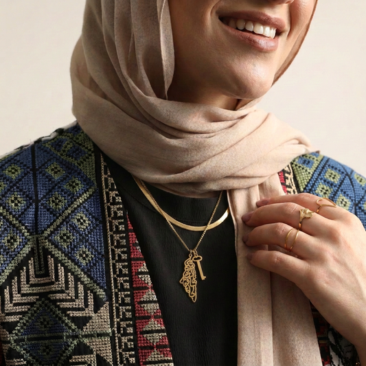 Model wearing the gold Palestine Calligraphy & Key Necklace layered with a herringbone necklace