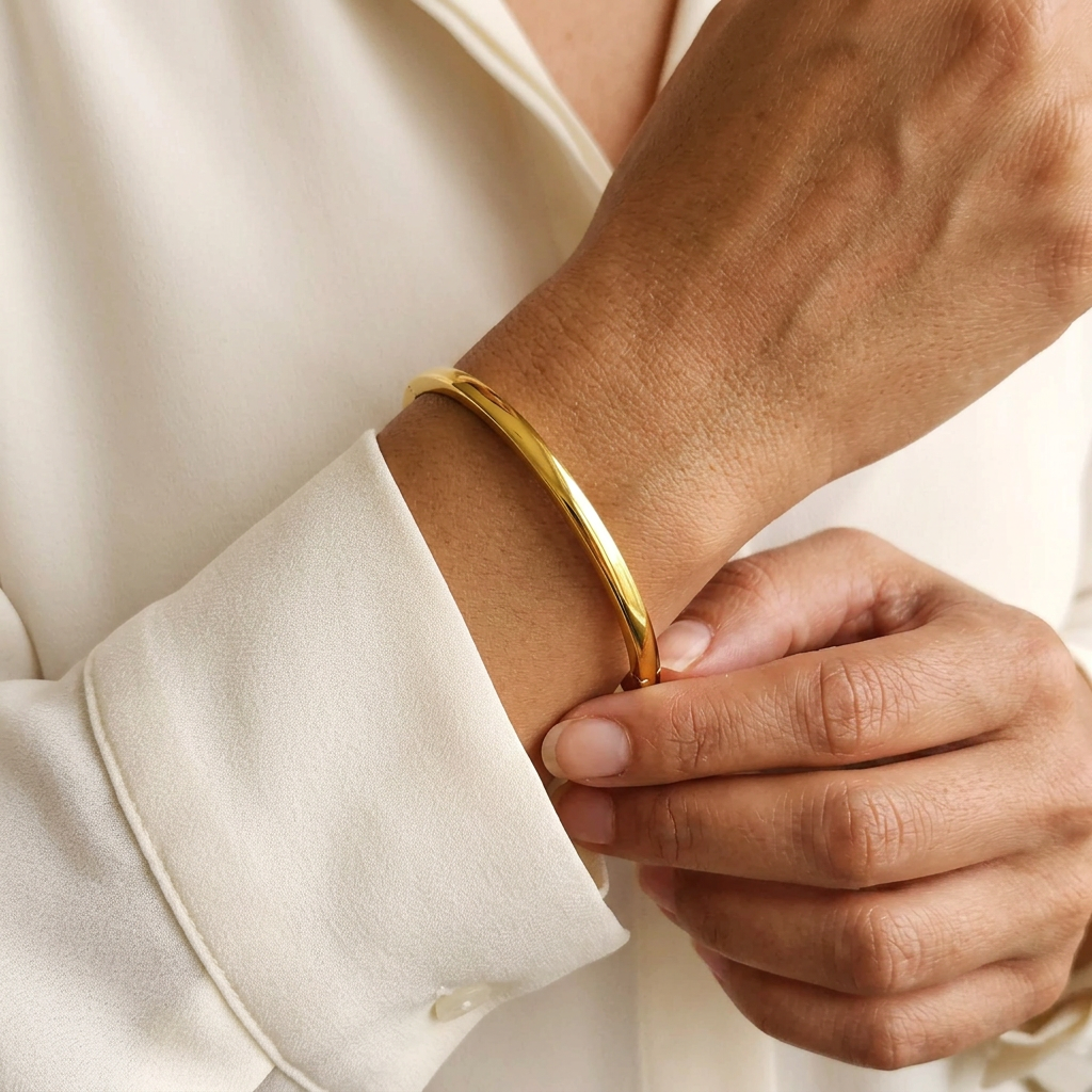 Model wearing the gold Plain Bangle, showing its slim polished band and fit around the wrist.