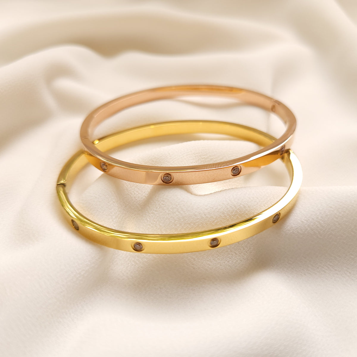 Rose-gold-tone and gold-tone Crystal Stud Bangles displayed together.