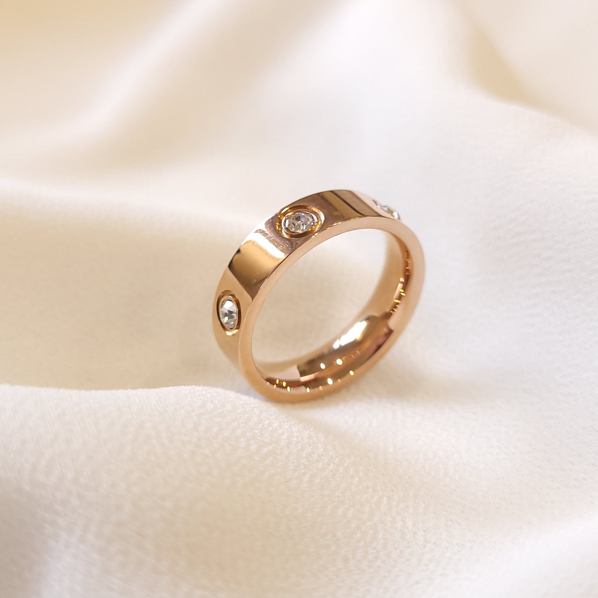 Rose gold-tone Crystal Stud Ring showing its polished band and round clear stones on cream fabric.
