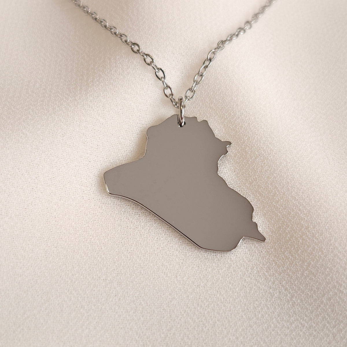 Silver-tone Iraq map pendant necklace with a fine oval-link chain.