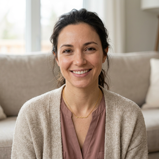 Smiling model wearing the gold-tone Cursive Mama Necklace with a mauve blouse and cream cardigan.