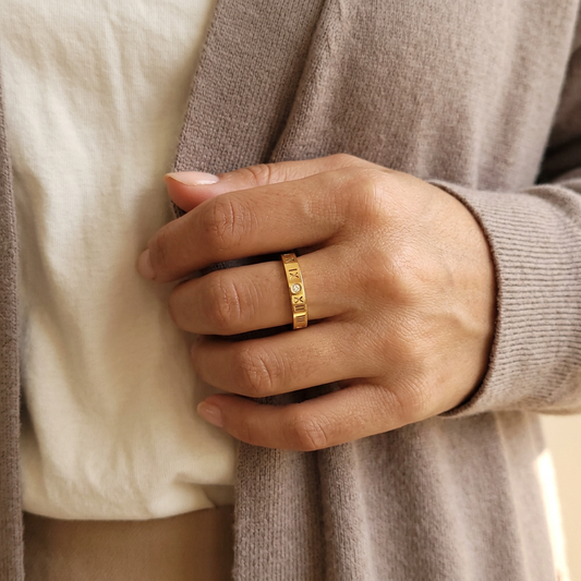 Natural hand-model preview wearing the gold Roman Numeral Band Ring, with relaxed everyday clothing