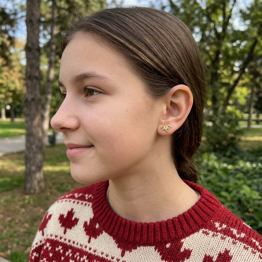 New square outdoor side-profile portrait of a teenage girl in a Canadian-inspired sweater wearing petite dragonfly studs