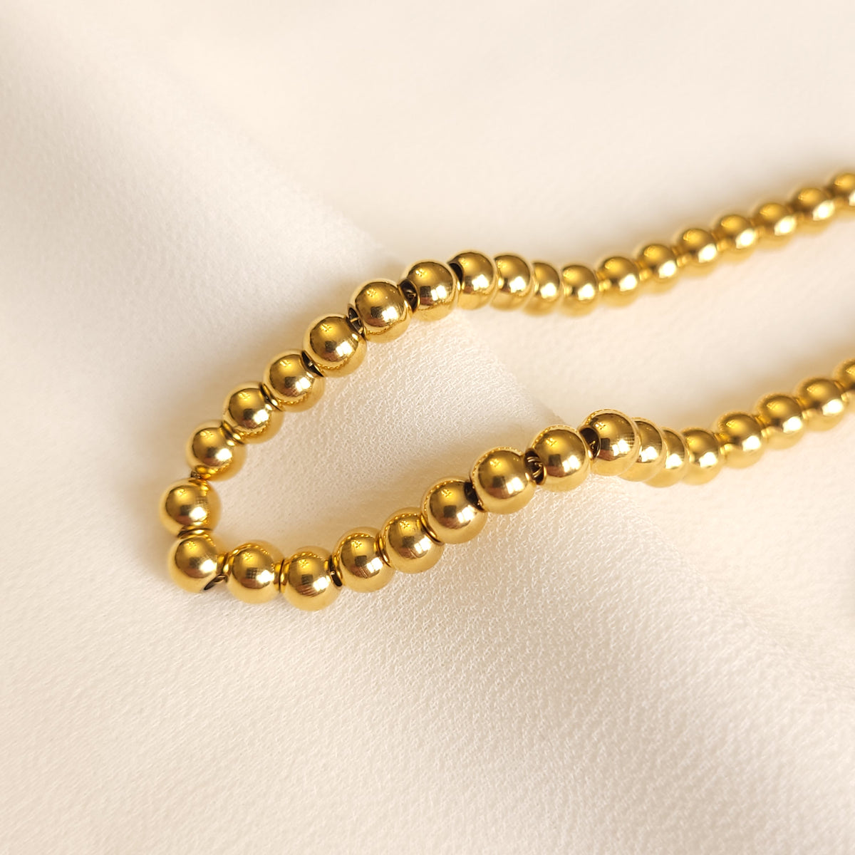 Beaded Bracelet close-up showing the smooth, reflective gold-tone beads and small connecting links.