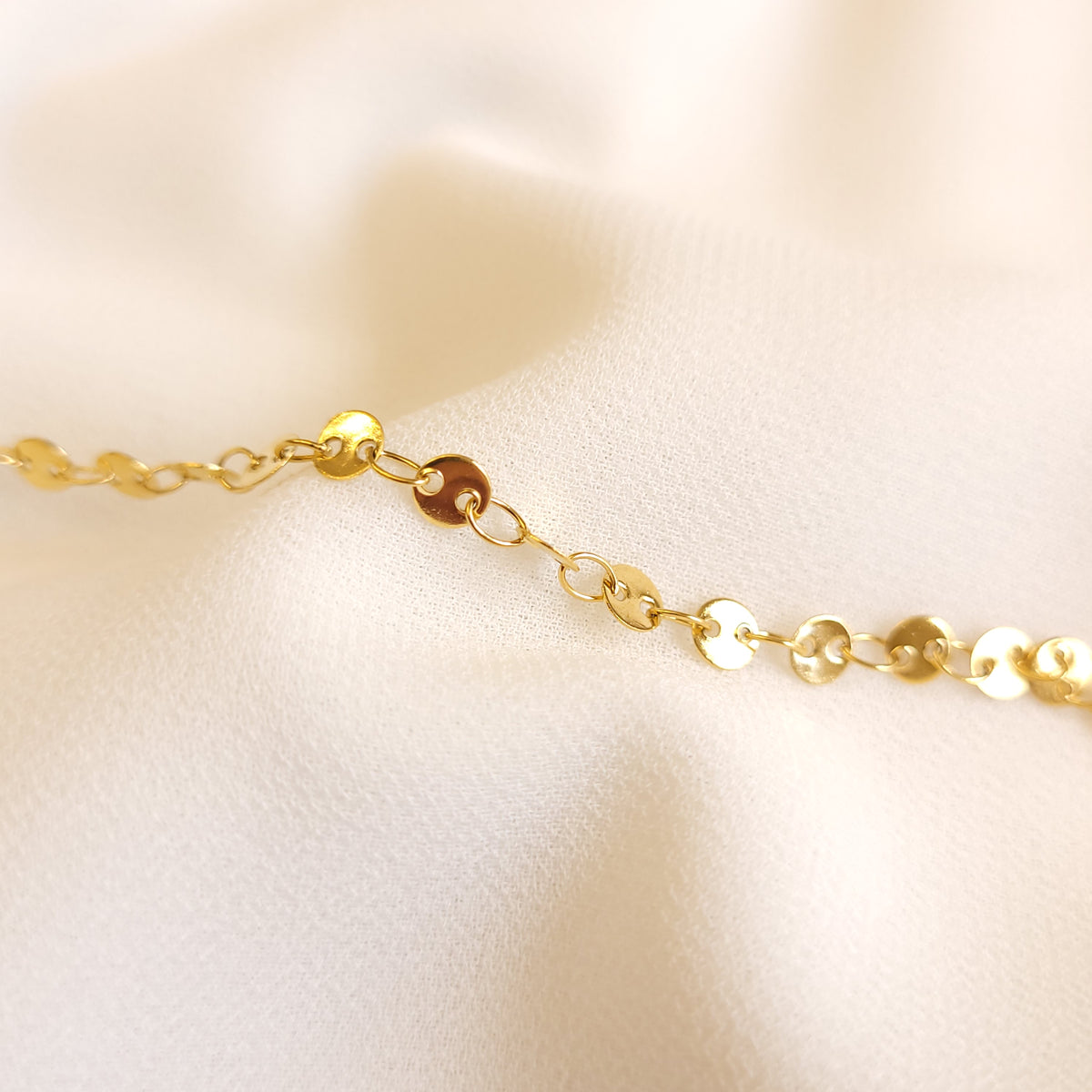 Coin Bracelet close-up showing the smooth, reflective gold-tone discs and connecting oval links.