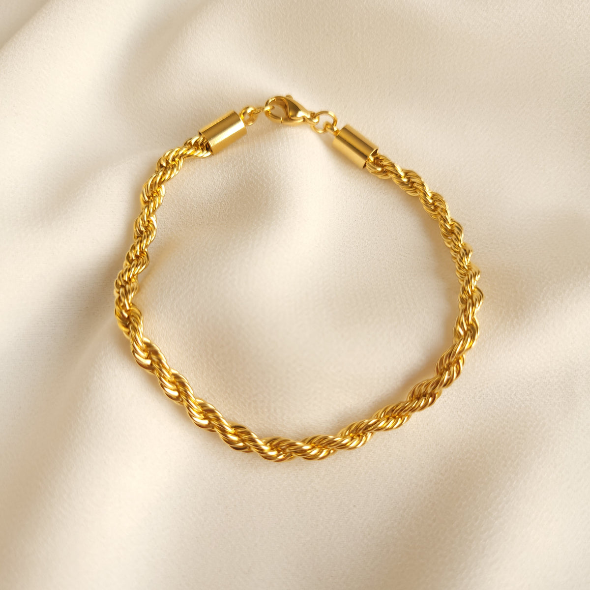 Rope Bracelet in gold tone arranged in a loop, showing intertwined links, a lobster clasp, and cylindrical end caps.