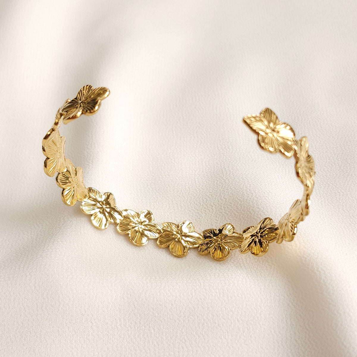 Angled view of the gold Flower Cuff showing its open ends and textured floral design