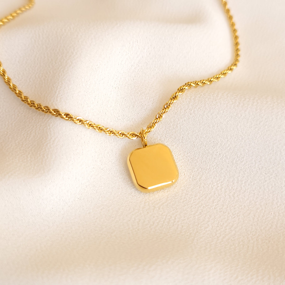 Back view of the Black Square Pendant showing its smooth gold-tone surface and rope chain.
