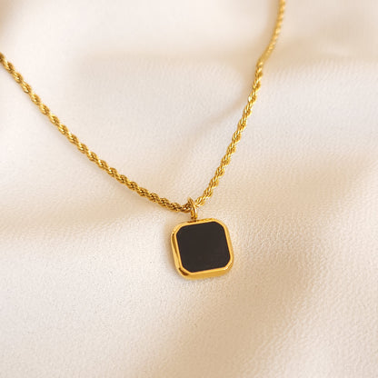 Black Square Pendant with a square black centre, clipped corners and a gold-tone frame on a rope chain.
