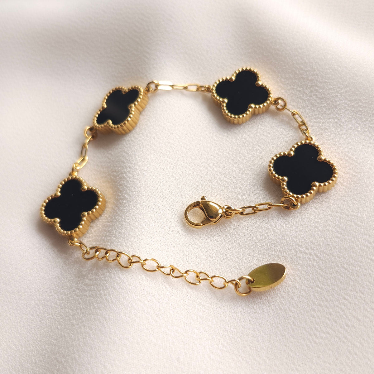 Children’s black clover bracelet laid open, showing the gold-tone clasp and extension chain.