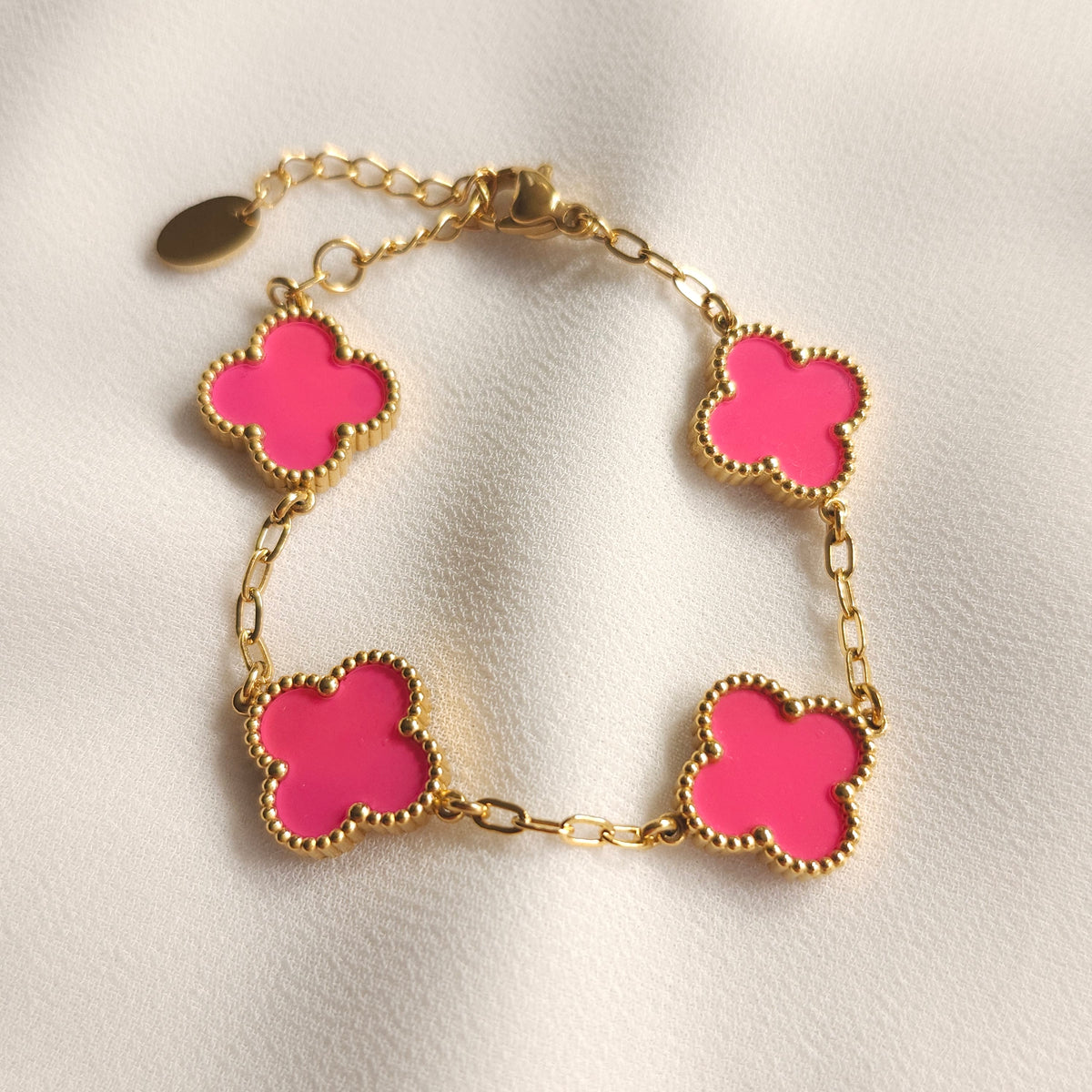 Children’s gold-tone bracelet with four bright pink clovers and beaded borders.