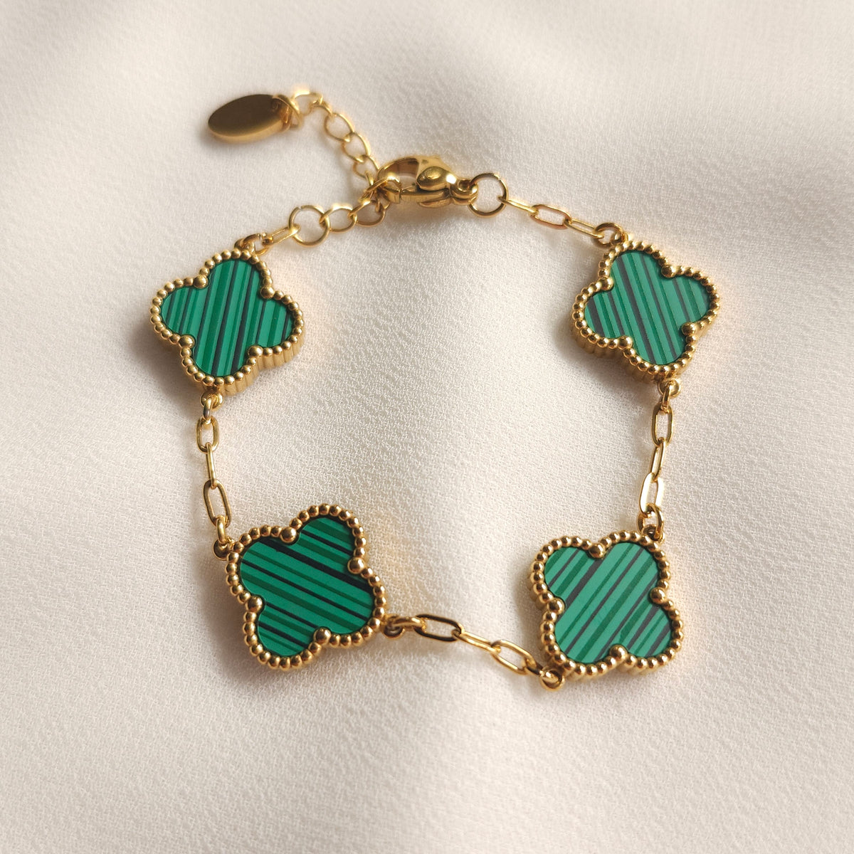 Children’s gold-tone bracelet with four green striped clovers and beaded borders.