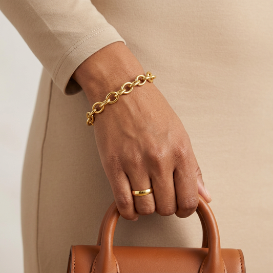 Circle Link Bracelet worn with a plain gold-tone band ring while holding a brown handbag.