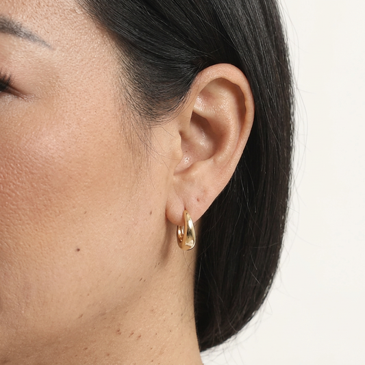 Close-up of a model wearing a gold-tone Basic Tapered Huggie Earring.
