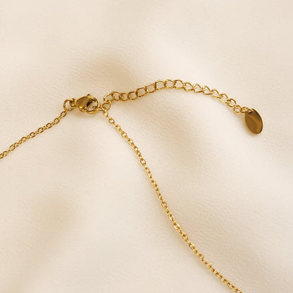 Close-up of the Arabic Initial Necklace’s gold-tone lobster clasp, extender chain and oval end tag.
