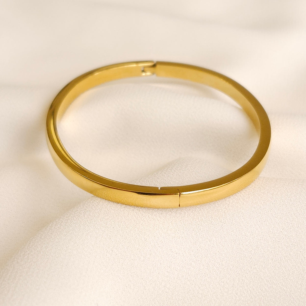 Close-up of the closed gold Plain Bangle showing its discreet clasp and polished finish.
