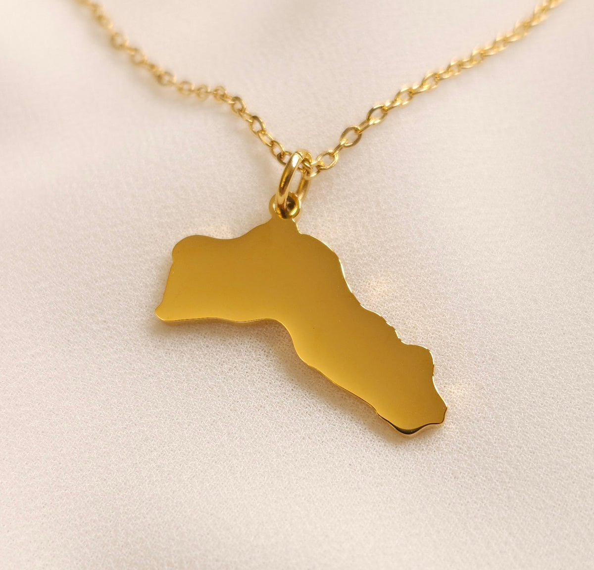 Close-up of the gold-tone Kurdistan map pendant and its polished edges.
