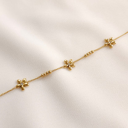 Close-up of the gold Daisy Chain Bracelet showing five-petal flowers and spaced groups of four beads.