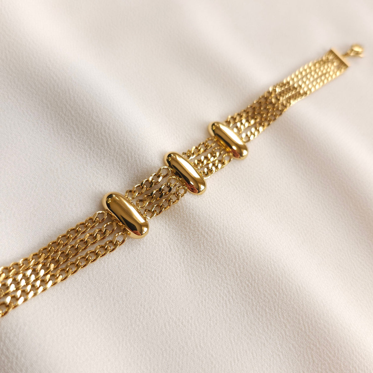 Close-up of the gold Trio Link Bracelet showing three rounded oval bars across parallel curb chains.