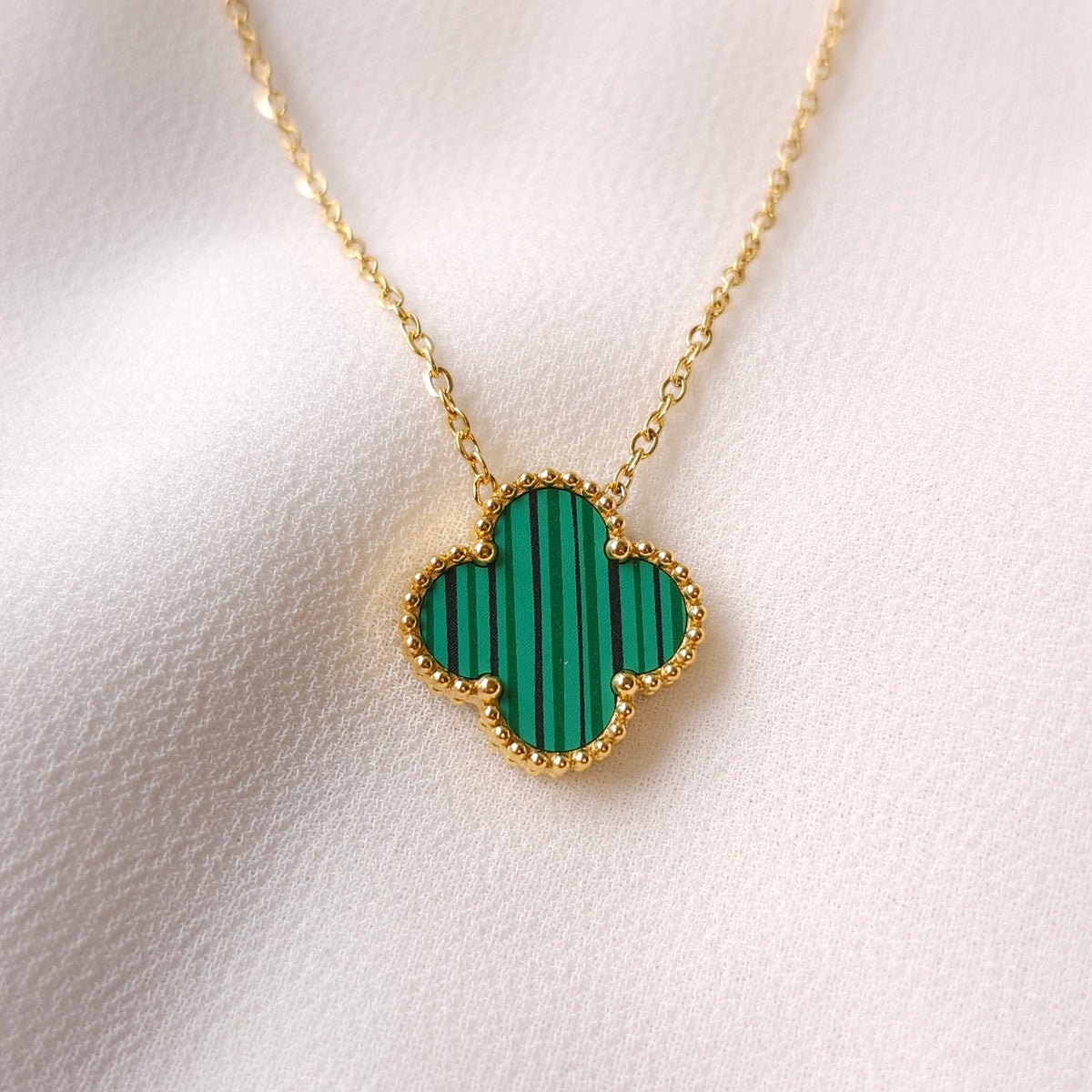 Clover Pendant Necklace close-up showing the striped green clover pendant with a gold beaded border and fine chain.