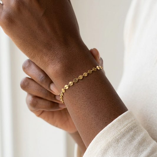 Coin Bracelet worn on a wrist, showing the delicate row of gold-tone discs against the skin.


