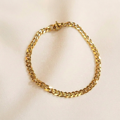 Dainty Cuban Chain Bracelet in gold tone arranged in a loop, showing polished curb links and a lobster clasp.