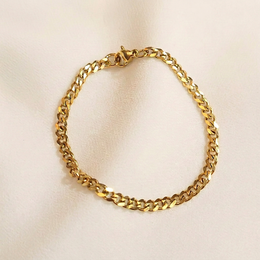 Dainty Cuban Chain Bracelet in gold tone arranged in a loop, showing polished curb links and a lobster clasp.