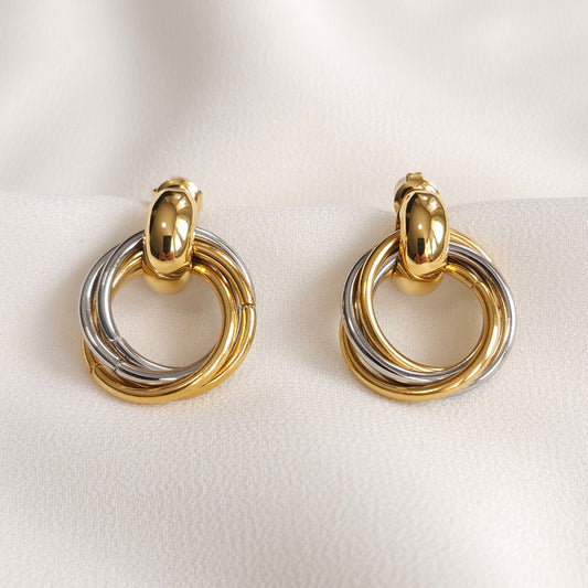 Dual Orbit Hoop Earrings with interlocking gold and silver hoops suspended from polished gold studs