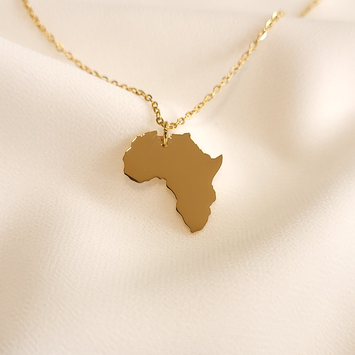 Gold-tone Africa map pendant necklace with a polished continent silhouette.
