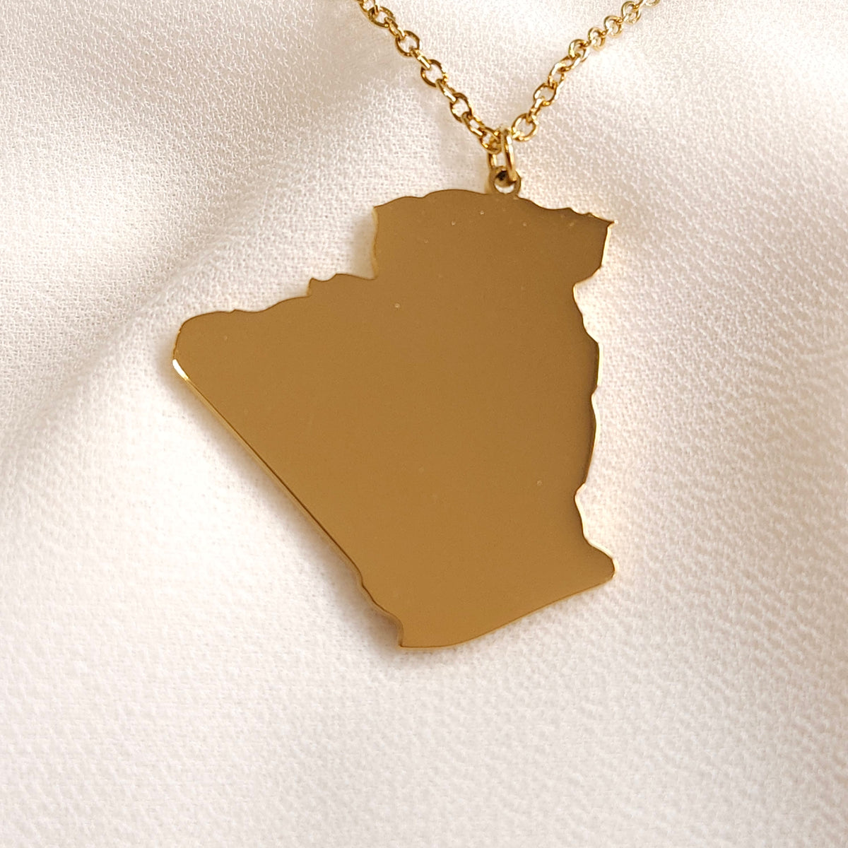 Gold-tone Algeria map pendant necklace with a polished silhouette.
