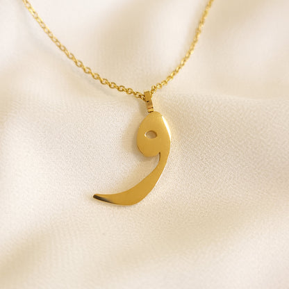 Gold-tone Arabic Initial Necklace with the letter Waw (و) on cream fabric.

