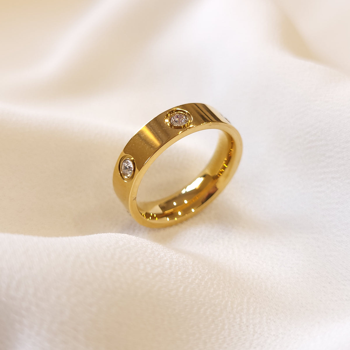 Gold-tone Crystal Stud Ring with a polished wide band and round clear stone accents.

