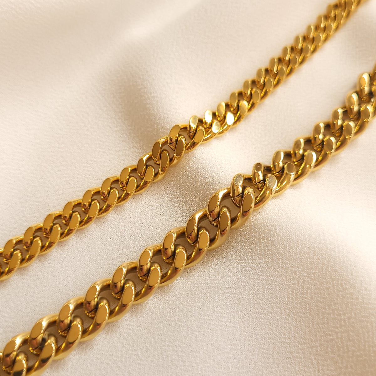 Gold-tone Cuban chain bracelets in two widths shown side by side, comparing their flattened links.
