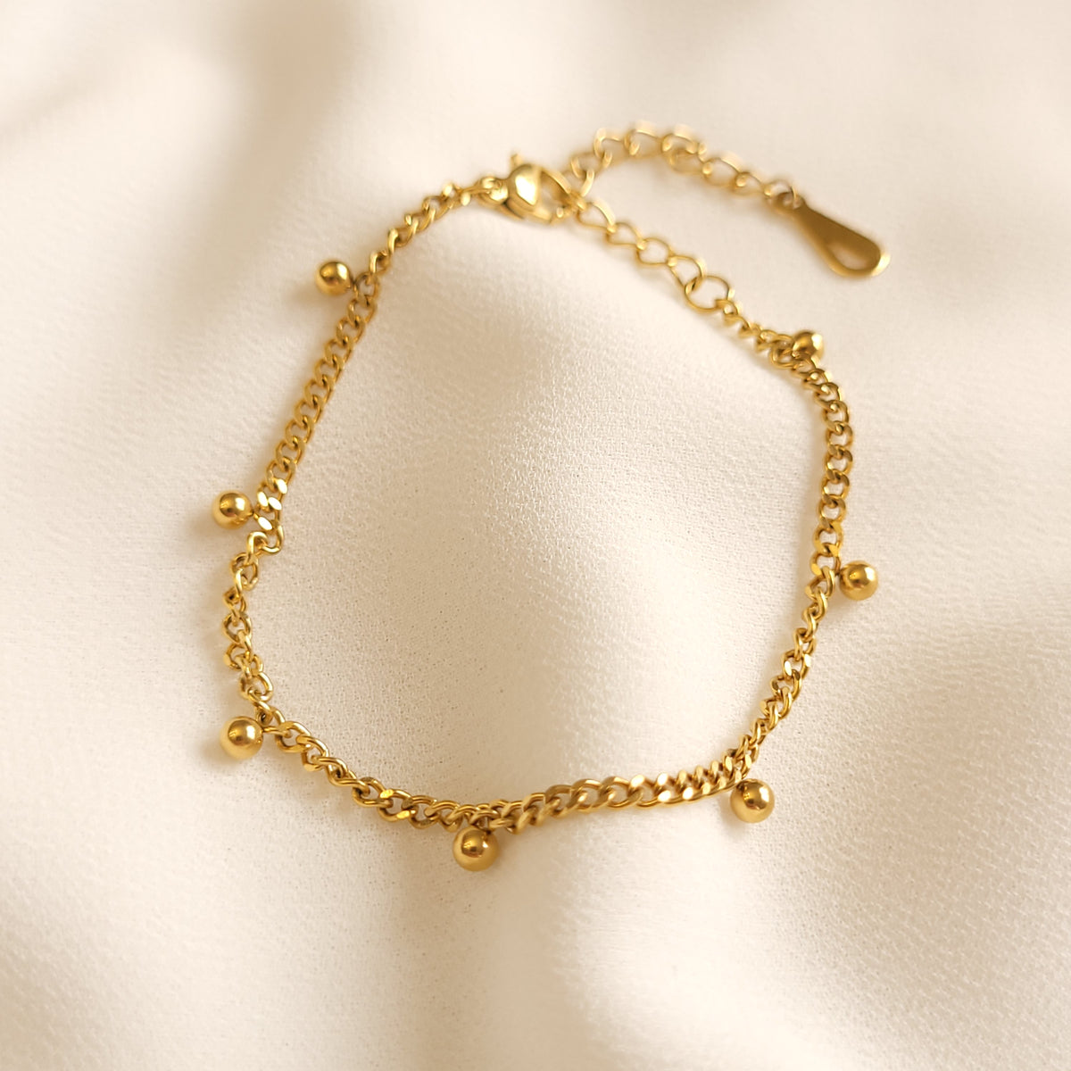 Gold-tone Dangling Dots Bracelet with a curb chain, small round dangling charms and an adjustable extender.

