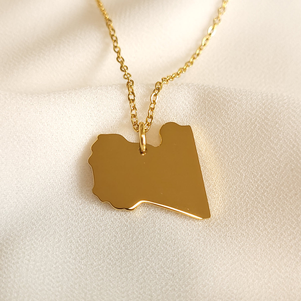 Gold-tone Libya map pendant necklace with a polished silhouette.
