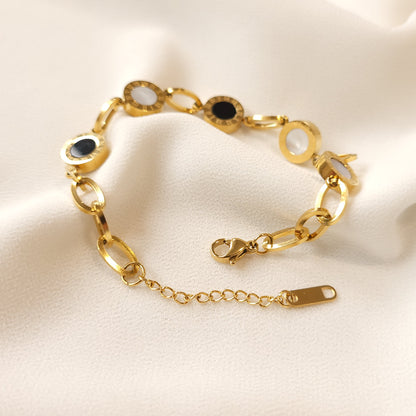 Gold-tone Roman Numeral Link Bracelet showing its lobster clasp, extender chain and rectangular end tag on cream fabric.