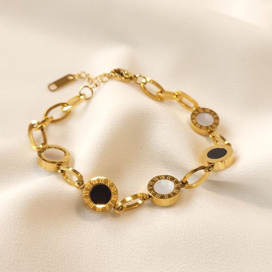 Gold-tone Roman Numeral Link Bracelet with alternating black and white round centres, engraved borders and oval connecting links.
